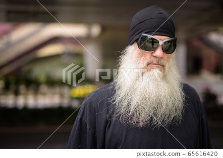 Face of mature bearded hipster man with sunglasses thinking in the city streets outdoors 65616420