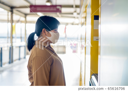 Profile view of overweight Asian woman with mask using self service locker box Profile view of overweight Asian woman with mask using self service locker box 65616706