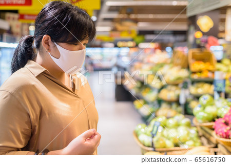 Profile view of overweight Asian woman with mask shopping inside supermarket Profile view of overweight Asian woman with mask shopping inside supermarket 65616750