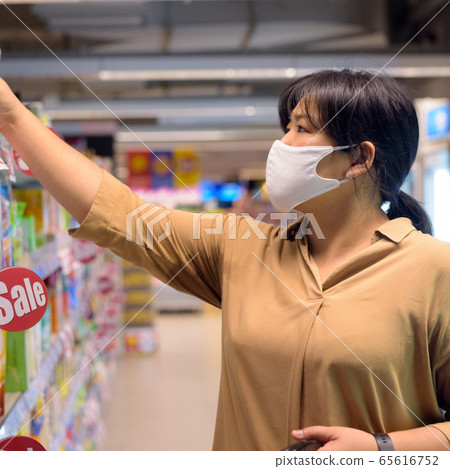 Overweight Asian woman with mask for protection from corona virus outbreak shopping inside 65616752