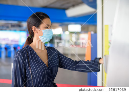Young Asian businesswoman with mask buying ticket at the skytrain station 65617089