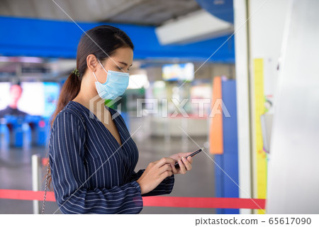 Young Asian businesswoman with mask buying ticket using phone at the skytrain station 65617090