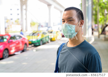 Face of young Asian man with mask for protection from corona virus outbreak at the taxi station in 65617517