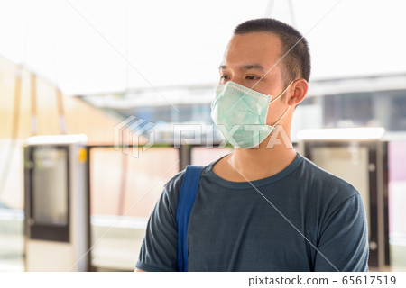 Young Asian man with mask for protection from corona virus outbreak thinking and waiting at the sky 65617519