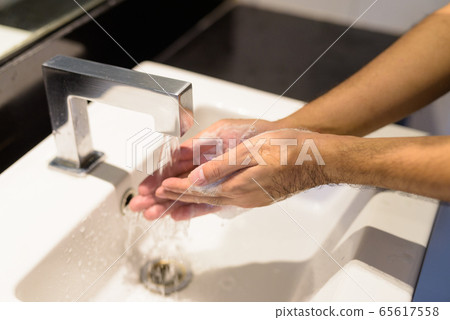 Hands of young man being washed and cleaned properly to prevent the spread of covid-19 Hands of young man being washed and cleaned properly to prevent the spread of covid-19 65617558