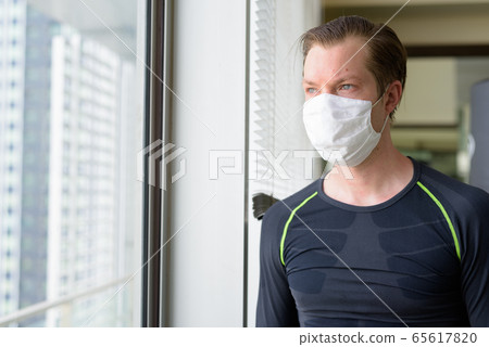 Young man with mask for protection from corona virus outbreak thinking of exercising during covid-19 65617820