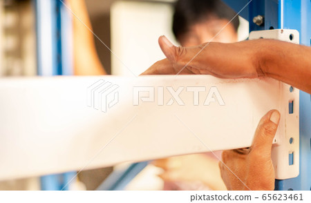 Male hand preparing to assembling the metal rack  in in warehouse or storage and shelves for cardboard boxes of products. 65623461