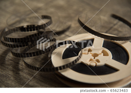 Unwound narrow retro film strip on a light reel on 65623483