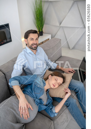 Young pregnant woman in a jeans jacket feeling tired laying on her husbands laps 65626880