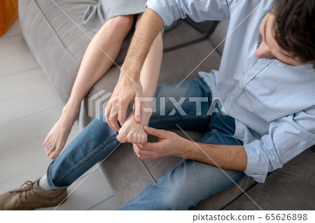 Dark-haired man making feet massage to his wife 65626898