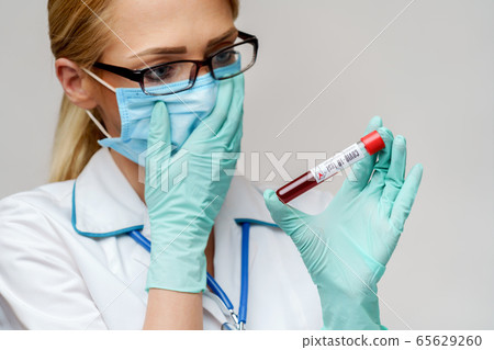 medical doctor nurse woman wearing protective mask and gloves - holding virus blood test tube 65629260