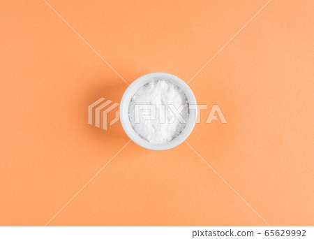 Baking soda in bowl on orange background Baking soda in bowl on orange background 65629992