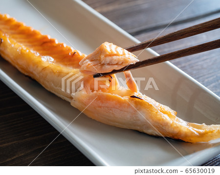 Close-up of chopping salmon harass grilled on the grill with chopsticks. 65630019