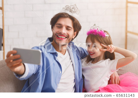 Happy father and daughter wearing as princesses taking selfie Happy father and daughter wearing as princesses taking selfie 65631143