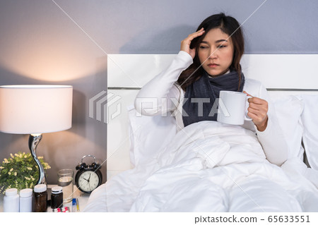 sick woman headache and drinking a cup of hot 65633551