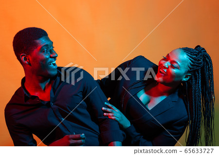 Portrait of young african american couple in love posing at studio dressed in classic clothes. Neon light. Portrait of young african american couple in love posing at studio dressed in classic clothes. Neon light. 65633727