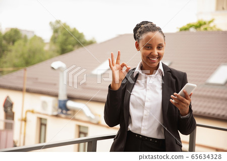 African-american businesswoman in office attire smiling, looks confident and happy, successful African-american businesswoman in office attire smiling, looks confident and happy, successful 65634328