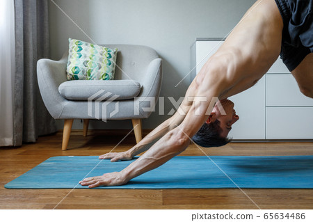 Man in upward dog pose doing vinyasa flow at home. 65634486