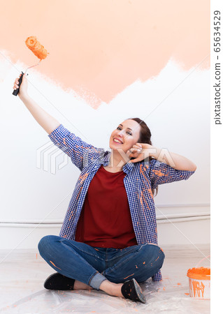 Renovation, redecoration and repair concept - Cheerful woman painting wall in new home. 65634529