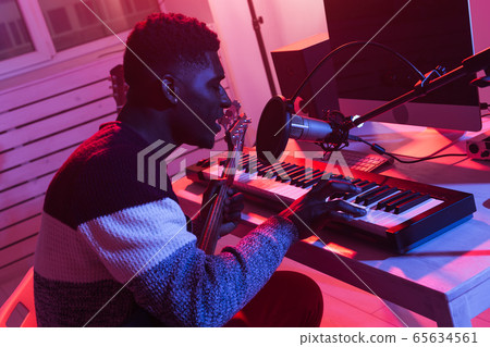 African american professional musician recording synthesizer in digital studio at home, music production technology concept. African american professional musician recording synthesizer in digital studio at home, music production technology concept. 65634561