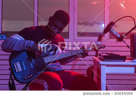 Create music and a recording studio concept - African american man guitarist recording electric bass guitar track in home studio Create music and a recording studio concept - African american man guitarist recording electric bass guitar track in home studio 65634564