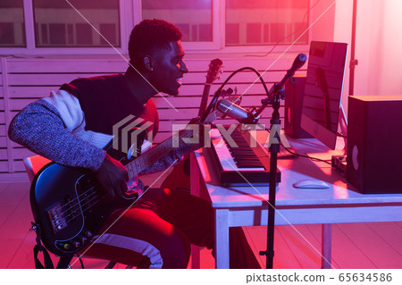 Create music and a recording studio concept - african american man guitarist recording electric guitar track in home studio Create music and a recording studio concept - african american man guitarist recording electric guitar track in home studio 65634586