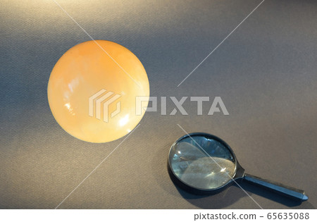 A magnifying glass and crystal ball on a black gray background 65635088