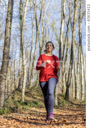 Pretty Spanish woman jogging in the forest in Pretty Spanish woman jogging in the forest in 65635413