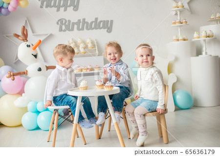 Cute little boys and girl at a table with birthday cakes at a children's party with balloons. Children's party. Balloons 65636179