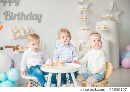 Cute little boys and girl at a table with birthday cakes at a children's party with balloons. Children's party. Balloons 65636197