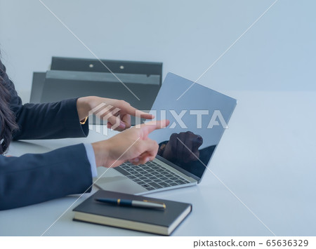 Close-up businessman's hand pointing on laptop screen over white desk at workplace. 65636329