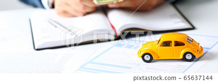 Insurance form lying on table with yellow toy car 65637144