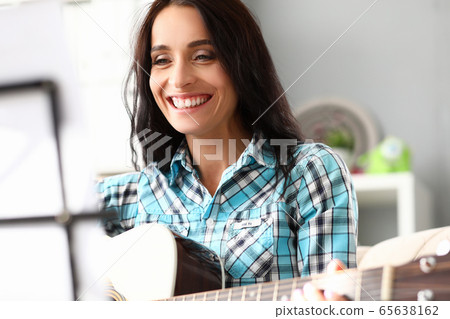 Beautiful woman plays guitar at home and laughs 65638162