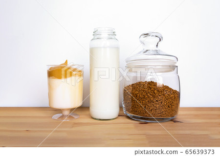 Dalgona coffee ingredients in jars on table. 65639373