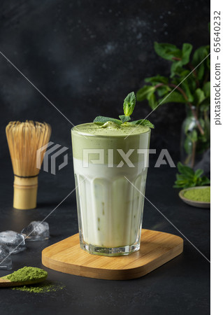 Glass of Dalgona Iced Matcha tea on black. 65640232