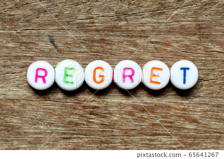 White bead with color letter in word regret on wood background 65641267