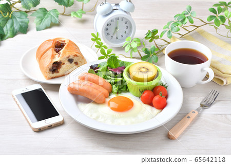 一盤早餐的圖像（西餐，煎蛋，香腸）。葡萄乾麵包，咖啡，智能手機和時鐘。 65642118