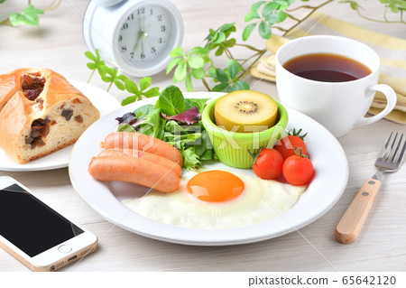 一盤早餐的圖像（西餐，煎蛋，香腸）。葡萄乾麵包，咖啡，智能手機和時鐘。 65642120