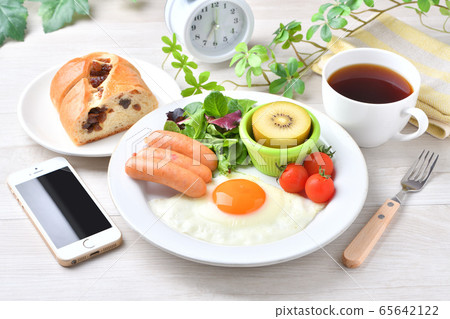 一盤早餐的圖像（西餐，煎蛋，香腸）。葡萄乾麵包，咖啡，智能手機和時鐘。 65642122