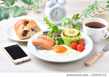 一盤早餐的圖像（西餐，煎蛋，香腸）。葡萄乾麵包，咖啡，智能手機和時鐘。 65642135