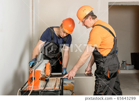Wet cutting a ceramic tile. 65643299