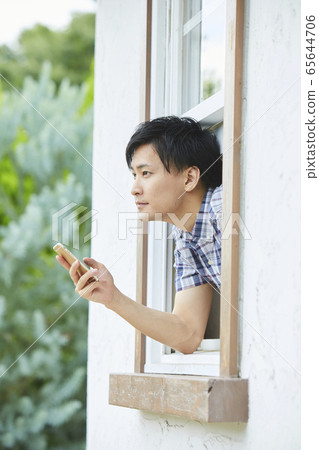Portrait of a young man showing his face through the window Portrait of a young man showing his face through the window 65644706
