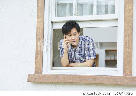 Portrait of a young man showing his face through the window 65644720