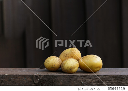 Fresh organic potatoes on the wooden table, copy space, dark background Fresh organic potatoes on the wooden table, copy space, dark background 65645319