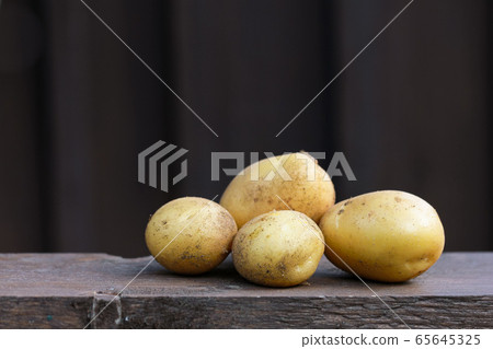 Fresh organic potatoes on the wooden table, copy space, dark background Fresh organic potatoes on the wooden table, copy space, dark background 65645325