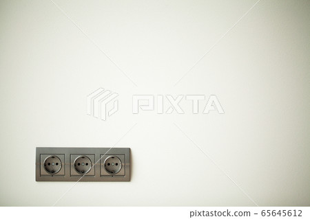Closeup view of a group of gray european electrical outlets located on a gray wall Closeup view of a group of gray european electrical outlets located on a gray wall 65645612