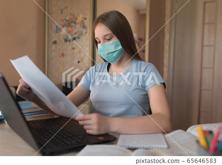 teenager girl of 12-15 years old, in medical mask, reads notes at home, laptop lessons. E-education and distance learning Internet video communications. Protection bacteria and covirus, stay home. teenager girl of 12-15 years old, in medical mask, reads notes at home, laptop lessons. E-education and distance learning Internet video communications. Protection bacteria and covirus, stay home. 65646583