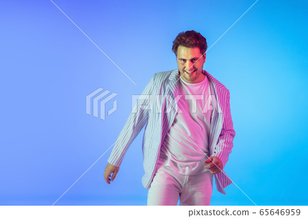 Young caucasian musician, dancer, party host, DJ on gradient background in neon light Young caucasian musician, dancer, party host, DJ on gradient background in neon light 65646959