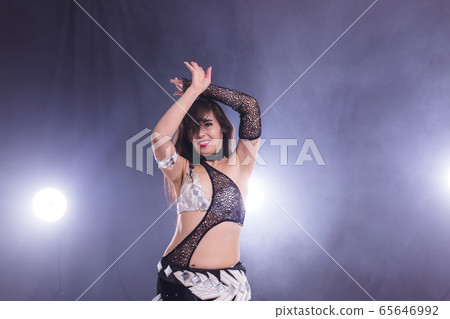 Young woman belly dancer in exotic dress with gold, dancing tribal fusion dance in studio. Young woman belly dancer in exotic dress with gold, dancing tribal fusion dance in studio. 65646992