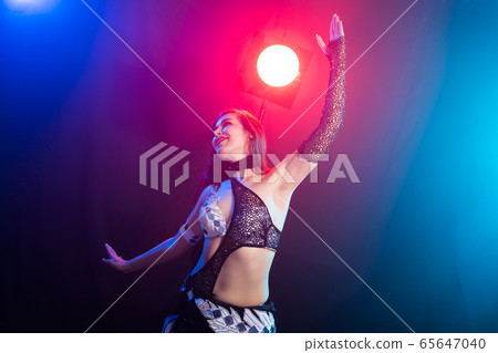 Young woman dancing in Tribal Fusion style. Belly dance on the stage. Young woman dancing in Tribal Fusion style. Belly dance on the stage. 65647040